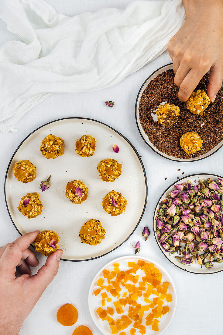 A man and a woman making pumpkin balls with diced apricot, flax seeds and rose petals accompany