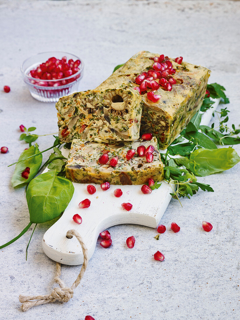 Mushroom terrine with pomegranate seeds on a bed of herbs