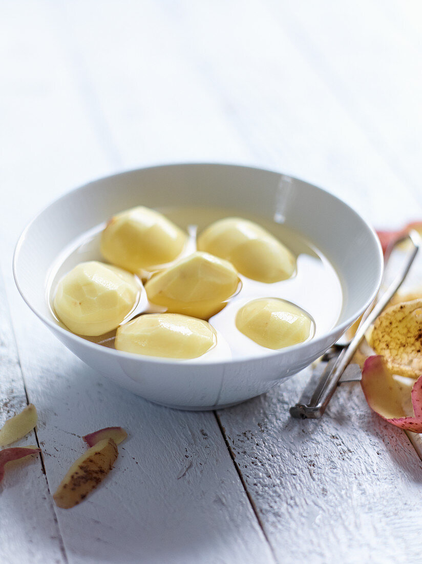 Peeled potatoes in a bowl of water