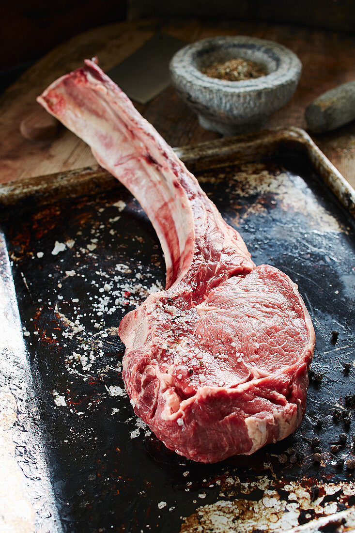 Dry-aged tomahawk steak on a baking tray