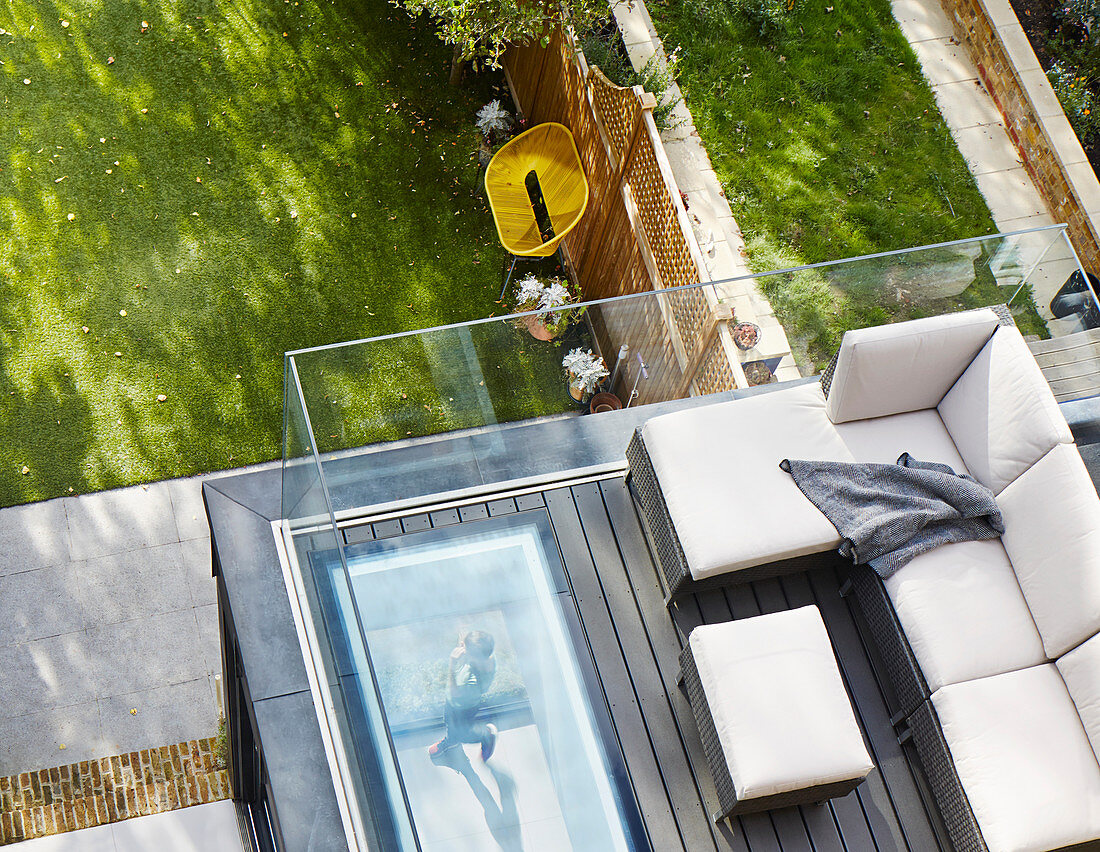 Sofa auf einer Dachterrasse mit Glasballustrade zum Garten