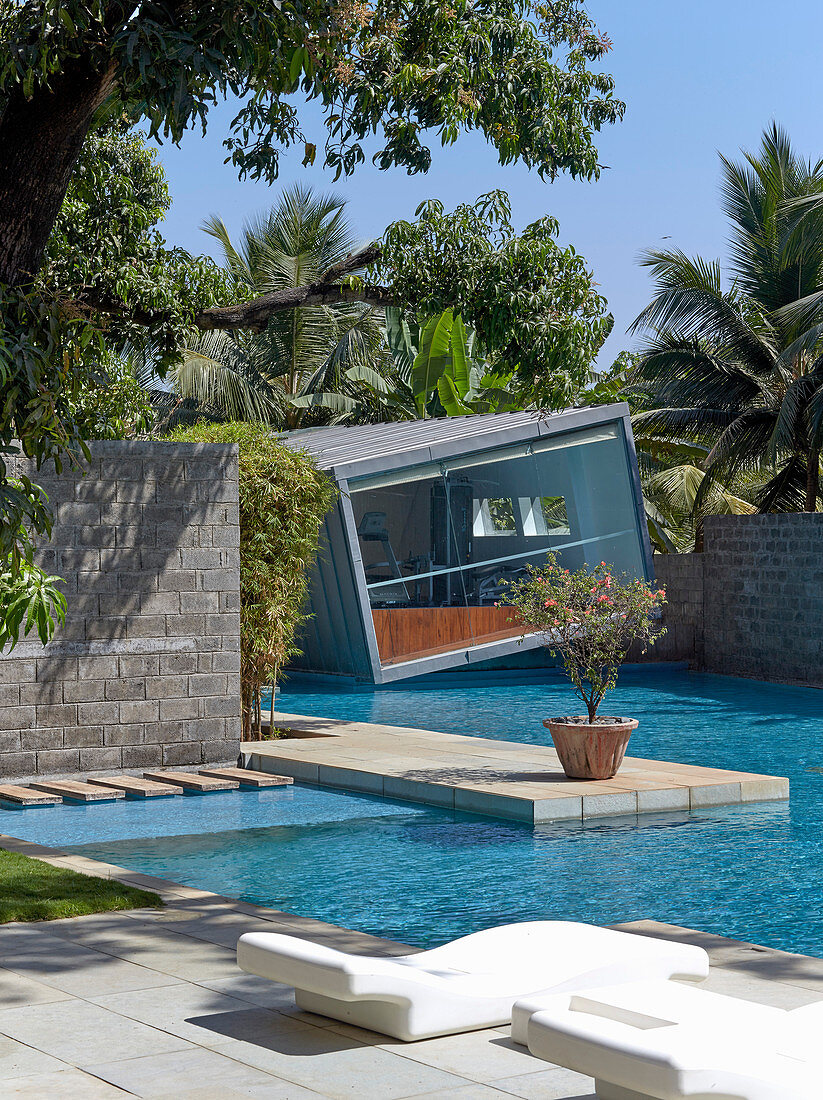 Slanted cube-shaped architect-designed house next to swimming pool
