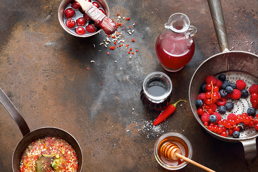 Fresh berries, barbecue marinade in a pan, and cherries in juice and honey