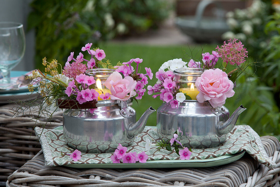 Tall glasses placed in silver teapots as lanterns,