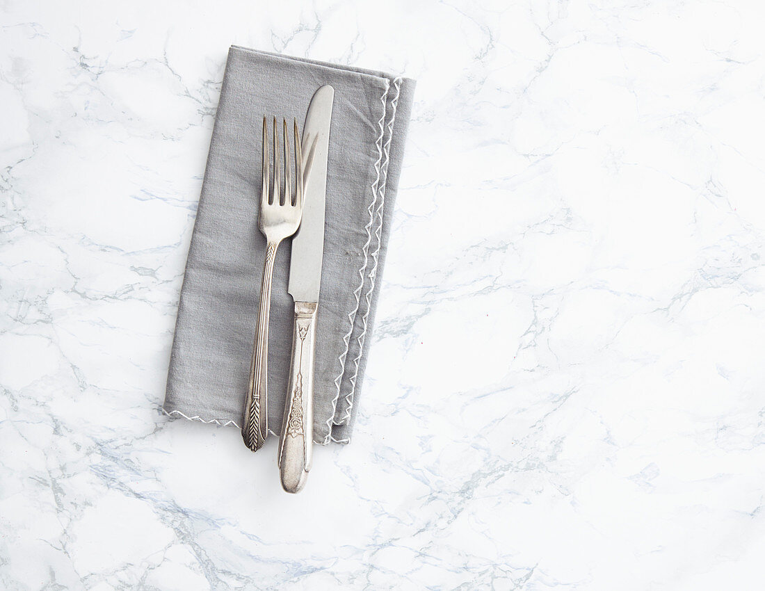 A grey napkin with a knife and fork