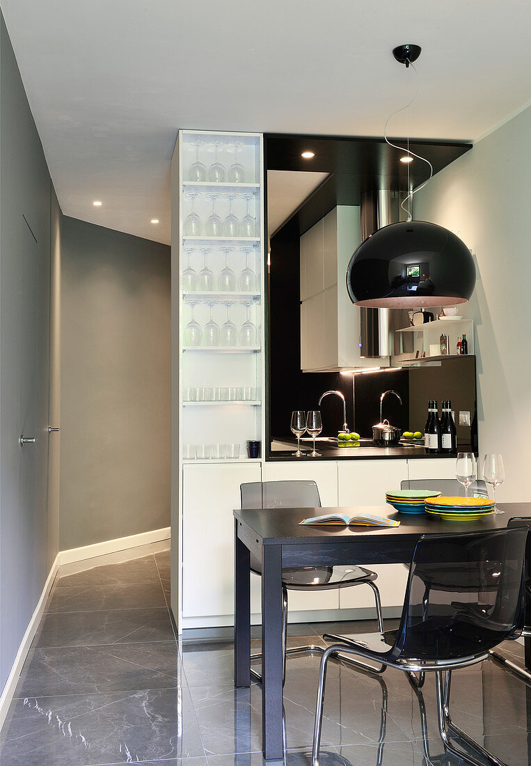 Black dining set in front of serving hatch leading to open-plan kitchen