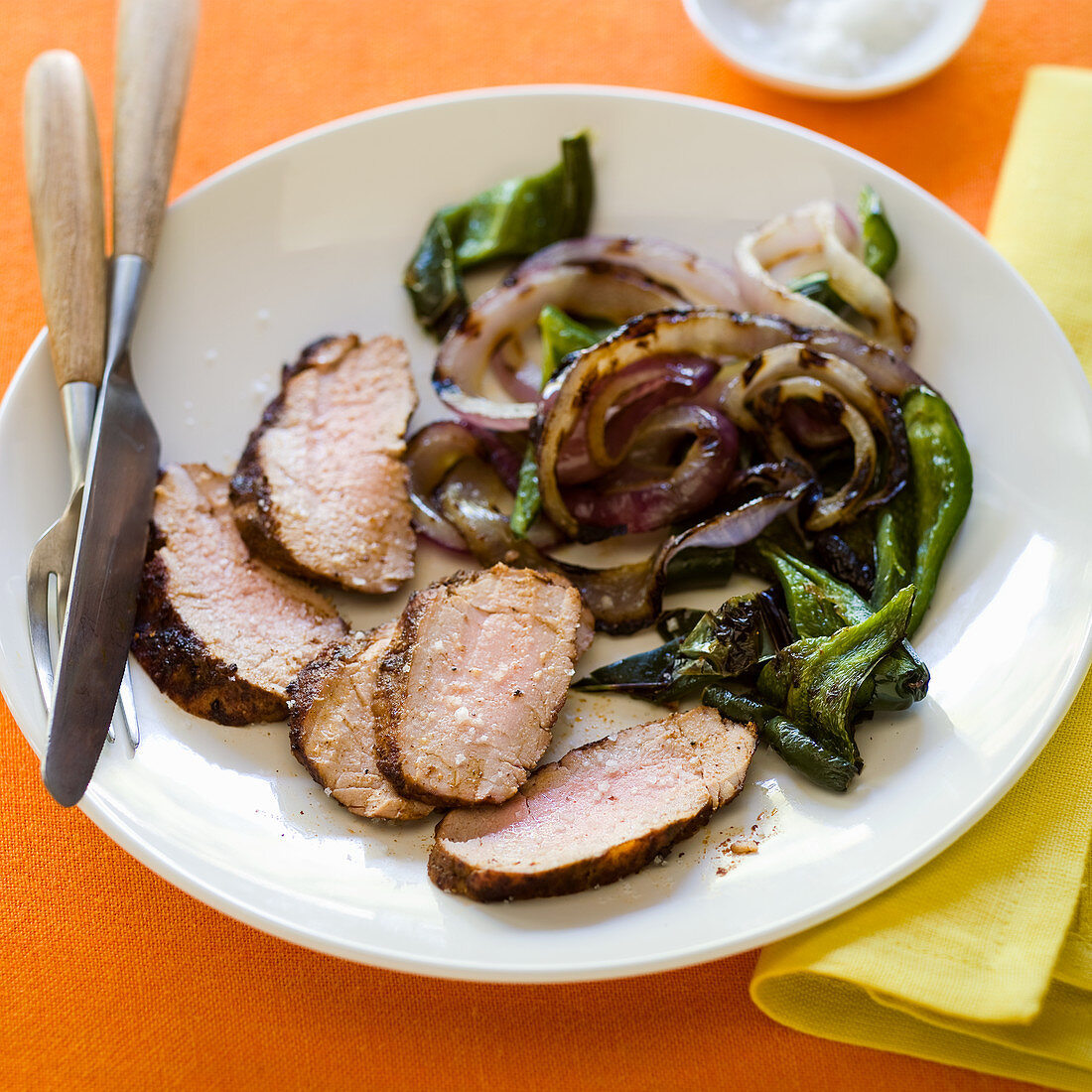 Sliced pork tenderloin with onions and greens