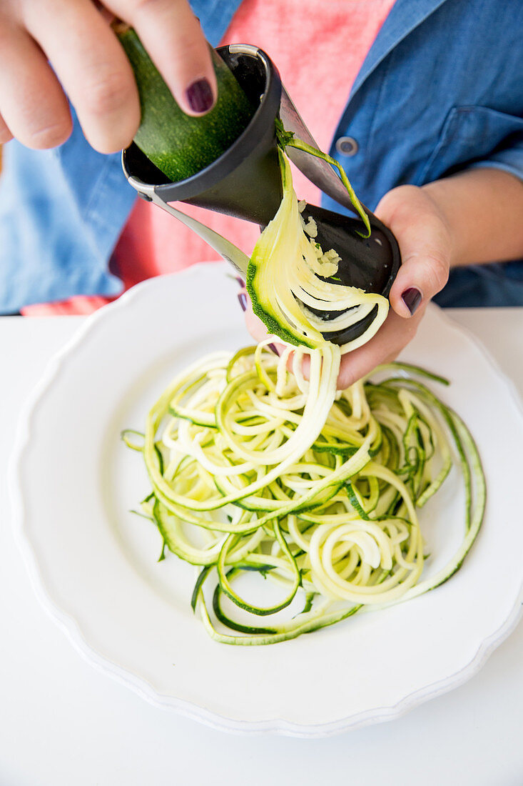 Courgette noodles being cut with a spiralizer