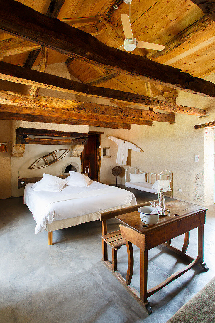 Old school desk and double bed in rustic bedroom