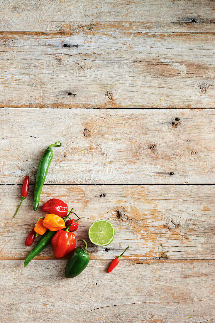 Various chili peppers on a wooden background
