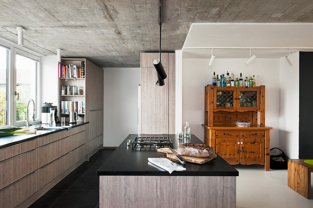 Moderne Küche mit grauen Fronten, Betondecke und altem Buffetschrank