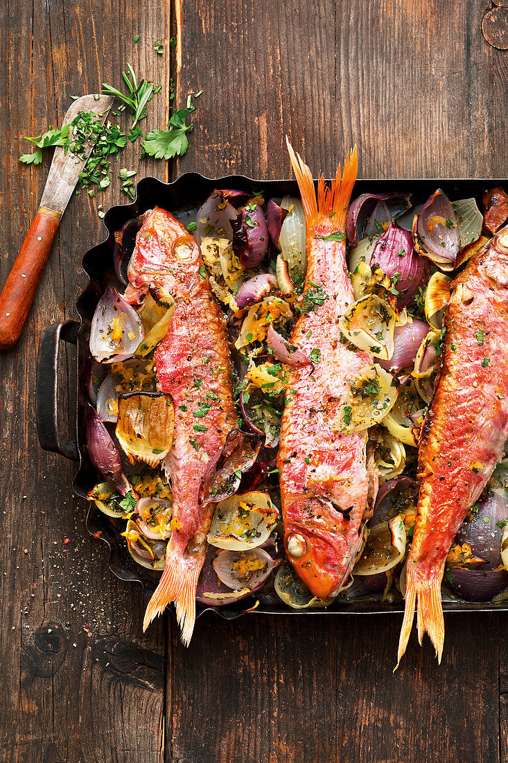 Grilled red mullet with an onion medley on a baking tray