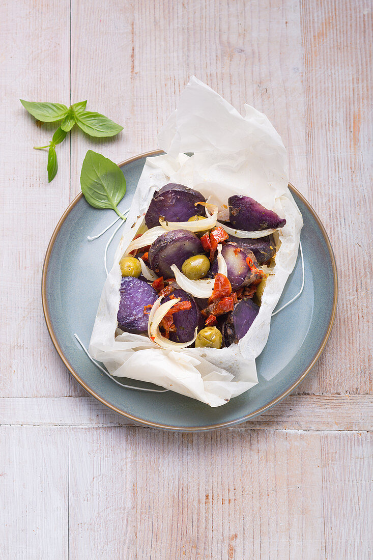 Blau-violette Ur-Kartoffelpäckchen mit Oliven aus dem Ofen