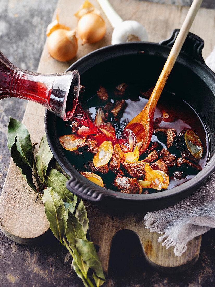 Angebratenes Rindergulasch mit Rotwein abgießen