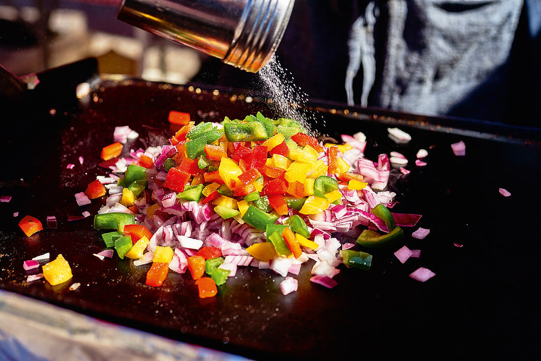 Street Food - Kleingeschnittenes Gemüse auf Grillplatte salzen