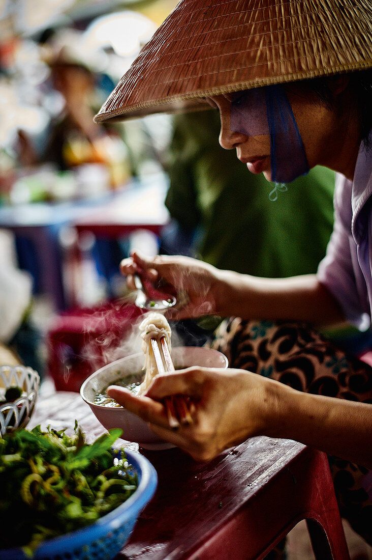 A Vietnamese woman eating pho bo noodle soup