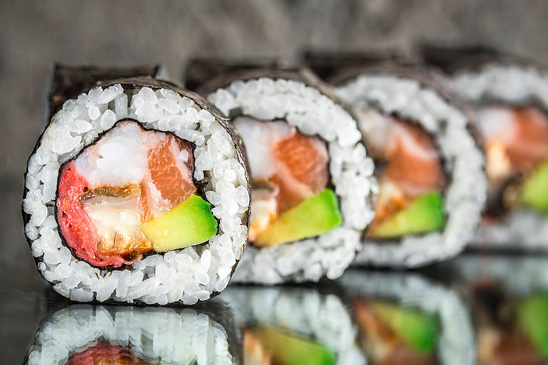 Sushi roll with salmon, shrimps and avocado over concrete background