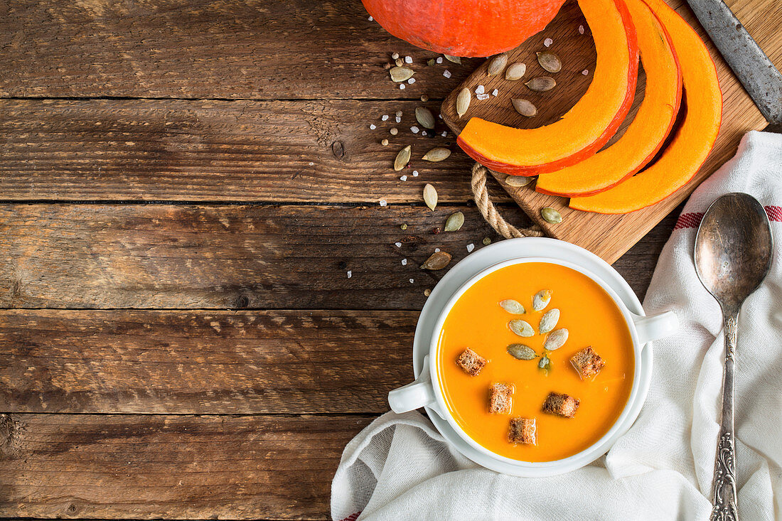 Pumpkin soup puree with seeds and wooden background