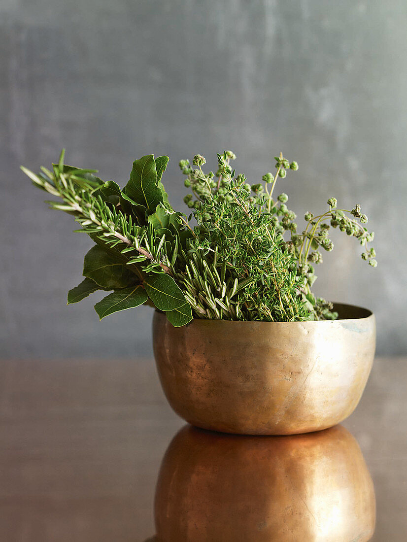 Various fresh herb sprigs in a copper cup