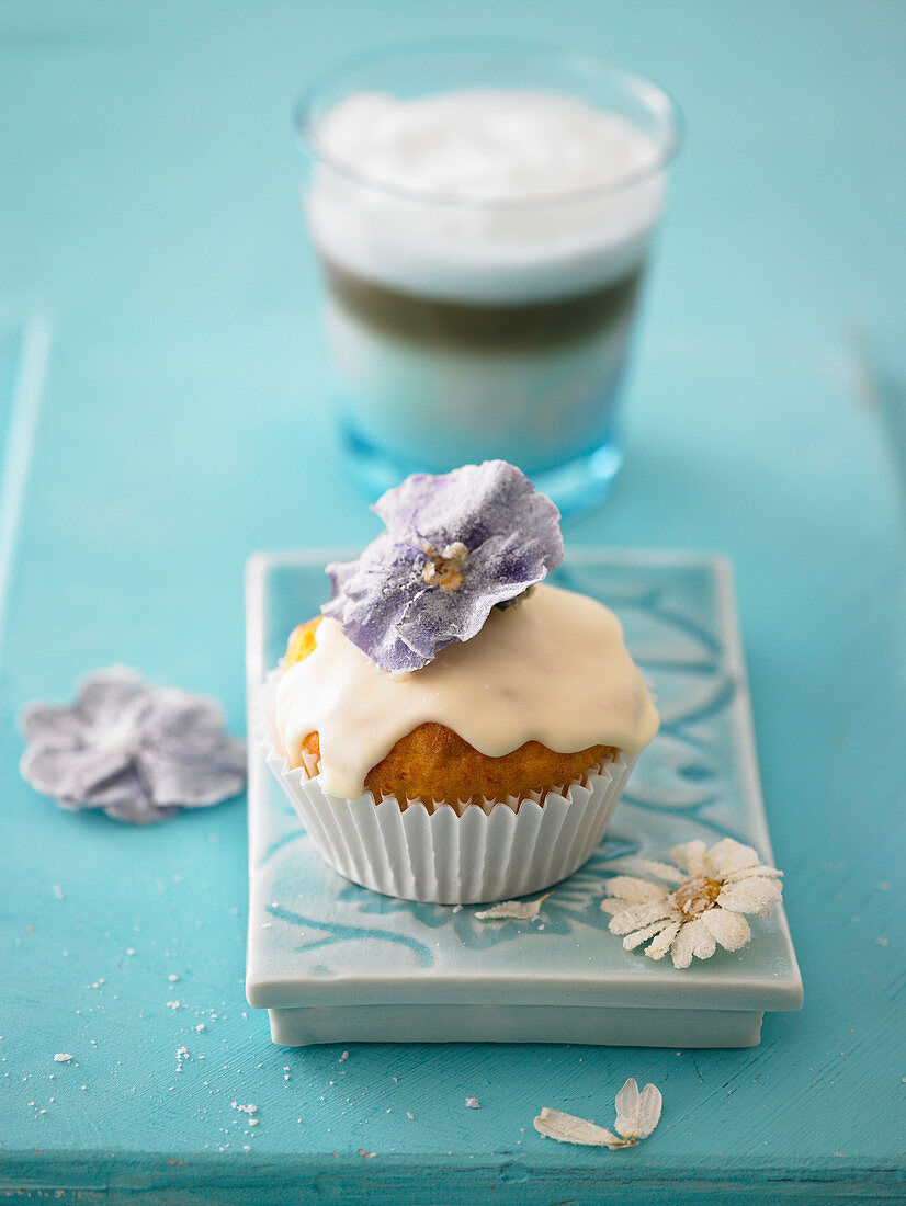 Ein Eierlikör-Muffin mit Glasur und gezuckerten Blüten