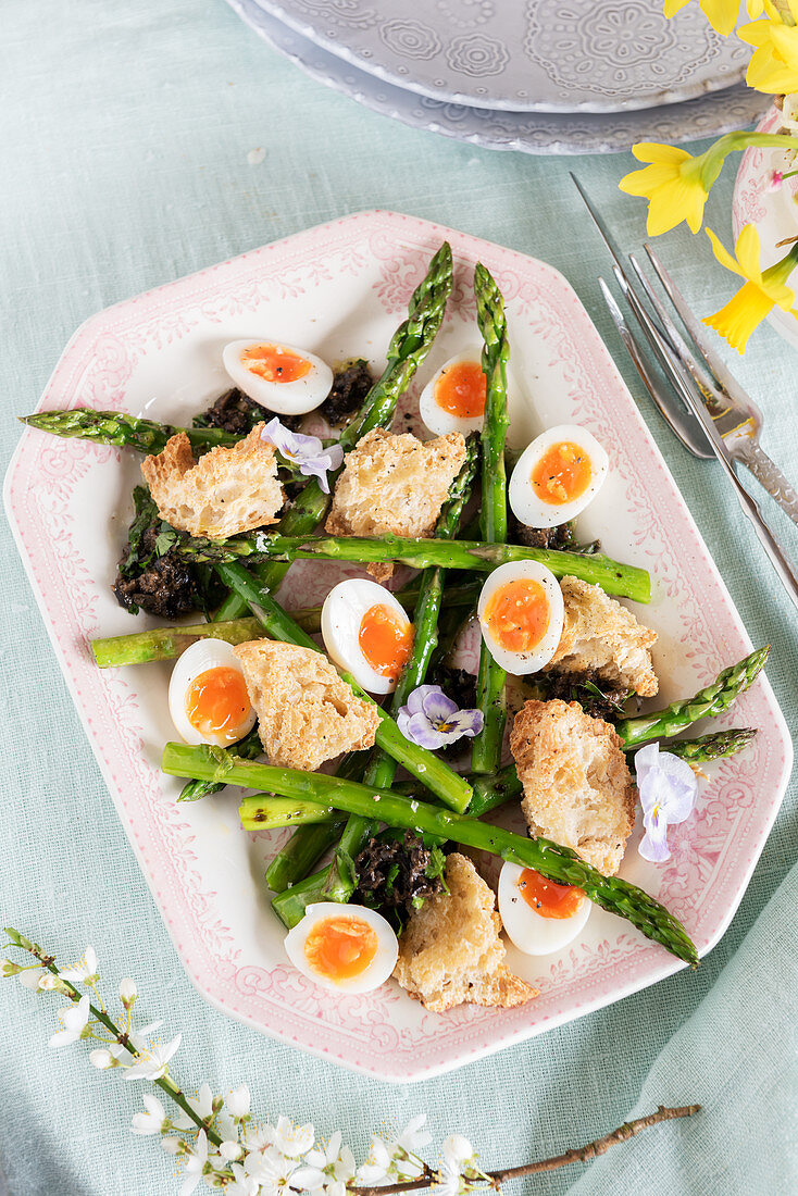 Grilled green asparagus with quail eggs, tapenade and bread