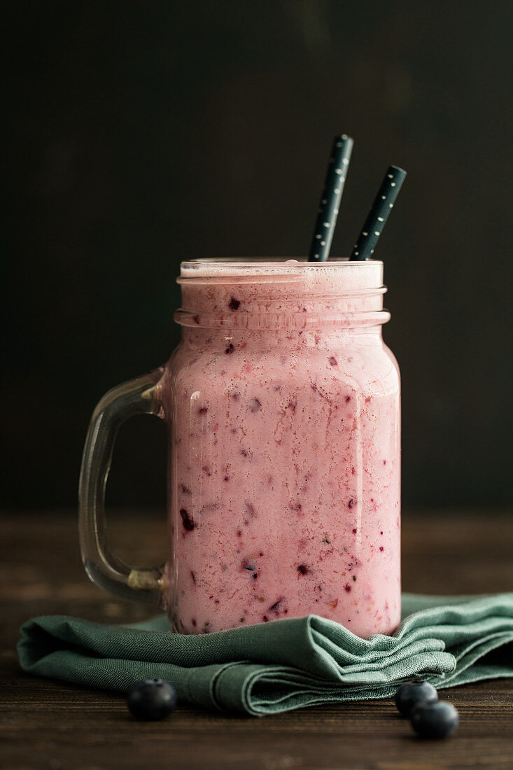 A smoothie with almond milk, berries and bananas in a jar with a handle