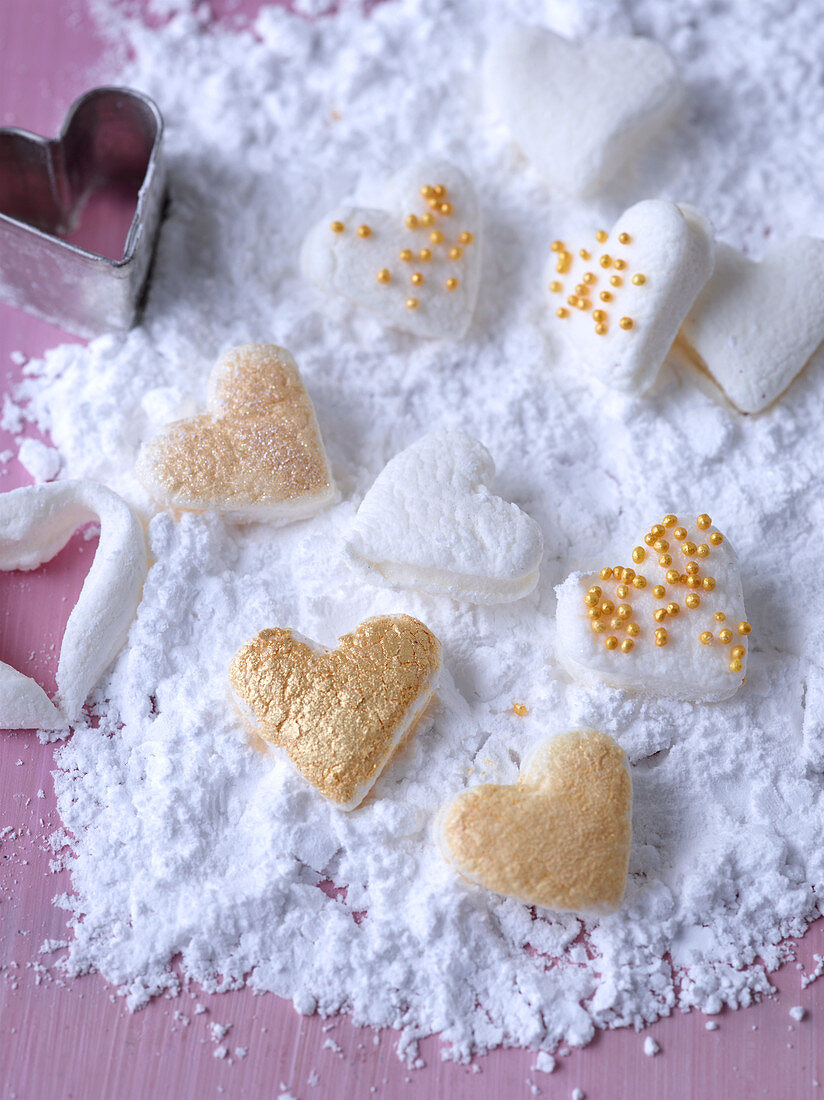 Marshmallow-Herzchen, mit Goldperlen verziert, in Puderzucker