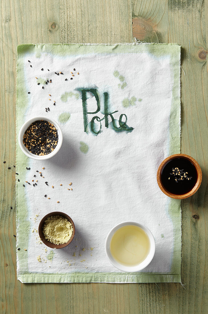Small bowls with various ingredients, a tea towel, and 'Poke' written