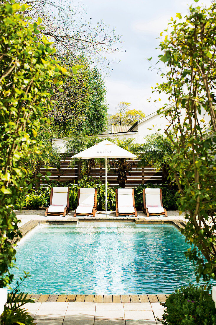 Loungers and parasol next to swimming pool