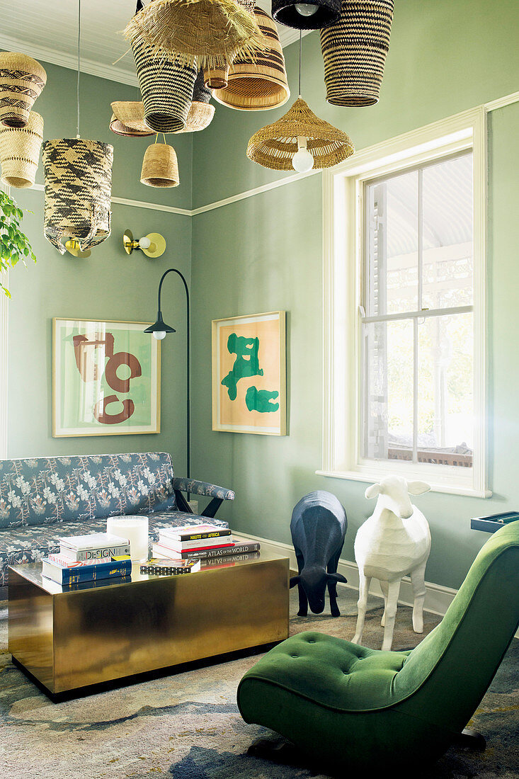Easy chair with green upholstery, animal sculptures, coffee table and sofa in lounge with green-painted walls