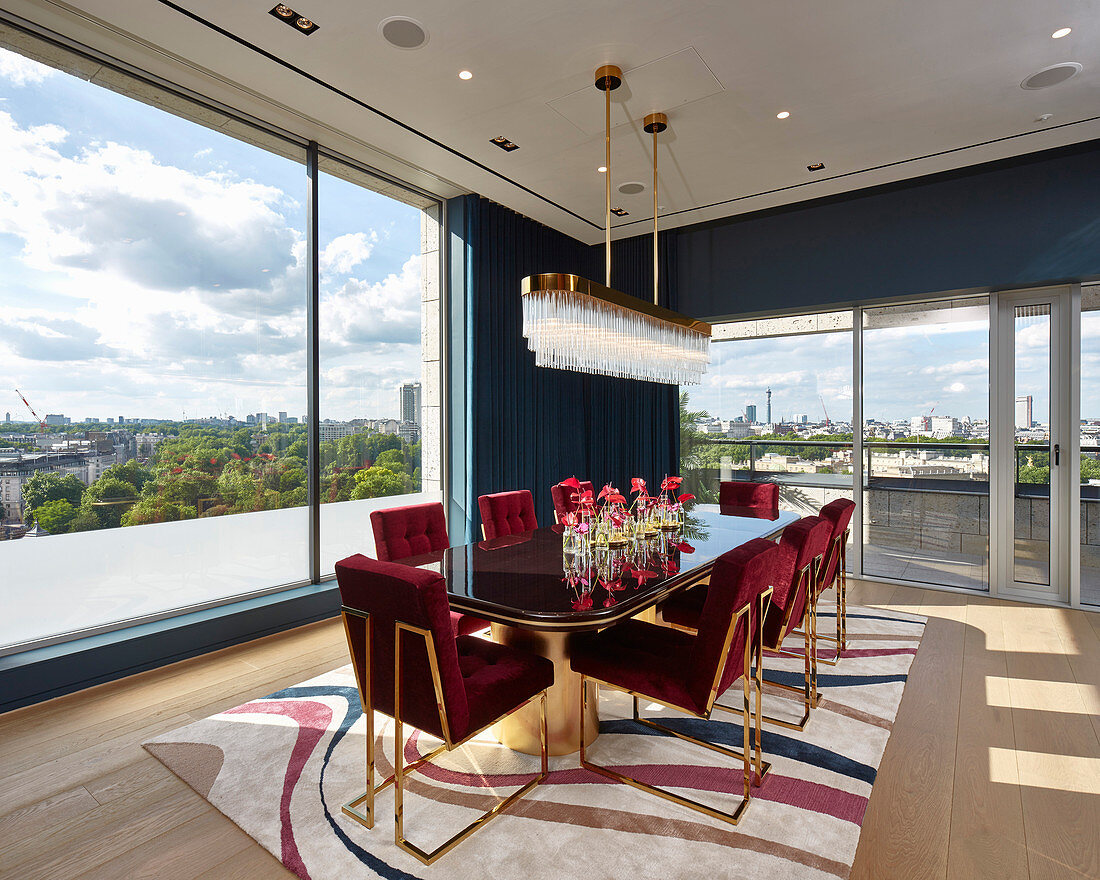 Red velvet chairs with gilt frames in dining room with panoramic view of city
