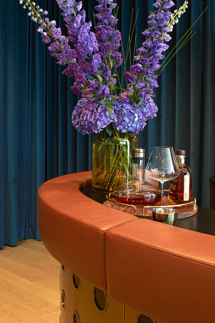 Vase of blue flowers and tray of bottles on bar