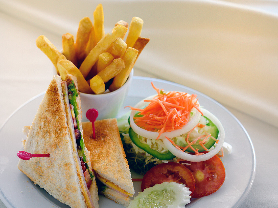 A club sandwich with a side salad and french fries
