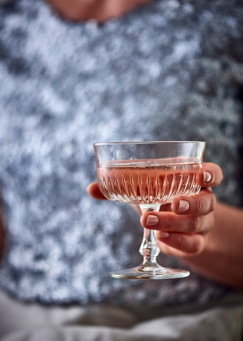 Frau hält ein Glas Rosesekt (weihnachtlich)