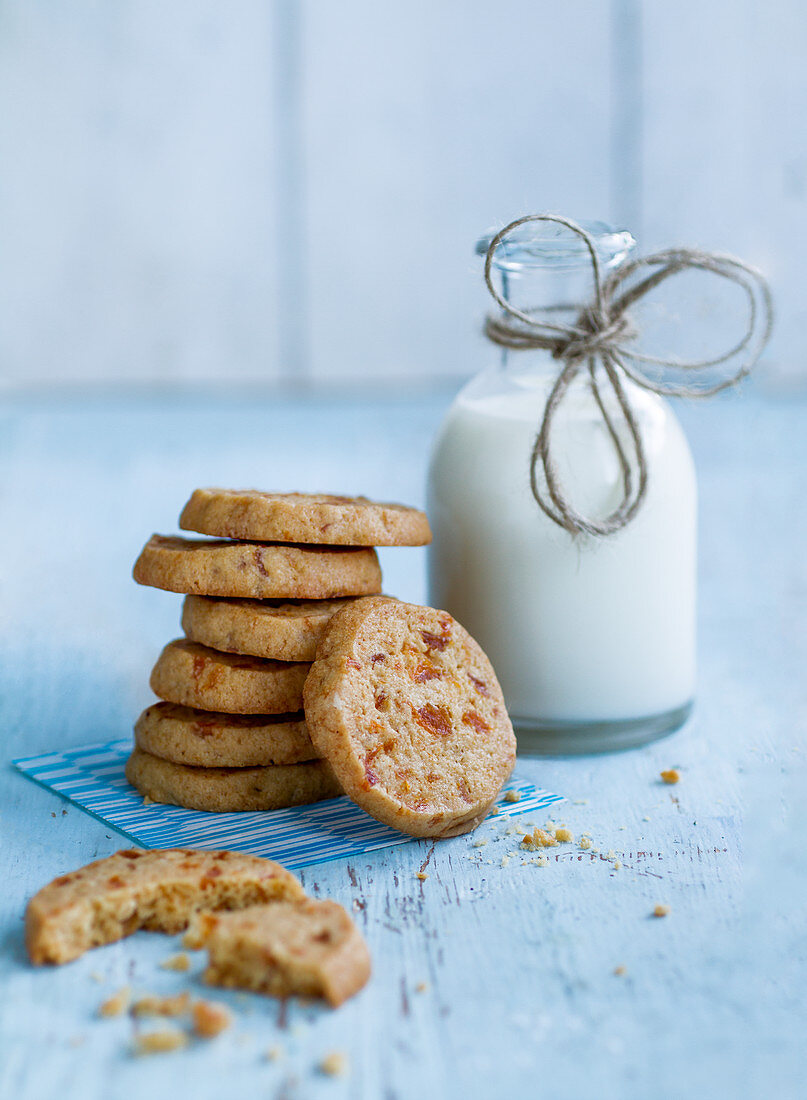 A stack of apricot biscuits next to a milk bottle