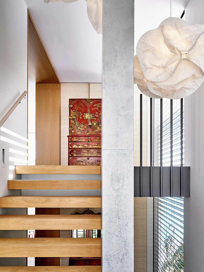 Designer-Pendelleuchte im Treppenhaus mit Stufen aus Eichenholz und Betonstütze