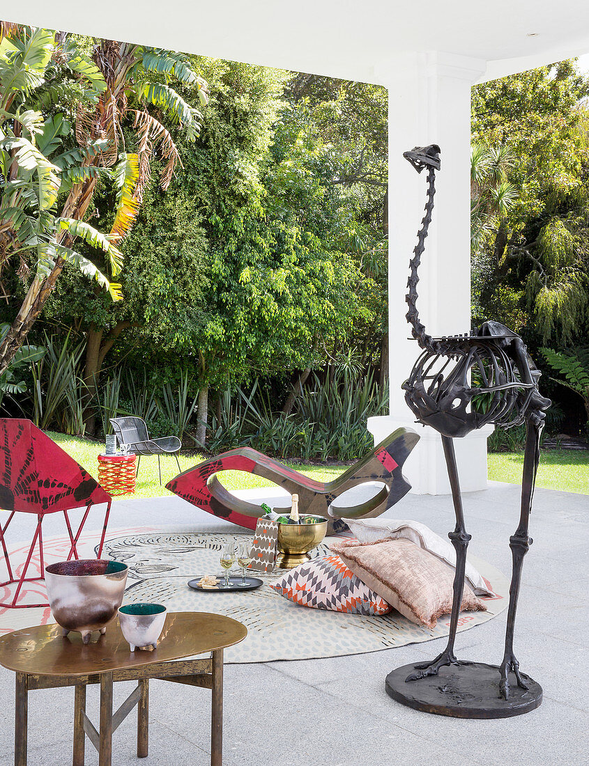 Sitzplatz mit Designermöbeln und Vogelskelett auf überdachter Terrasse