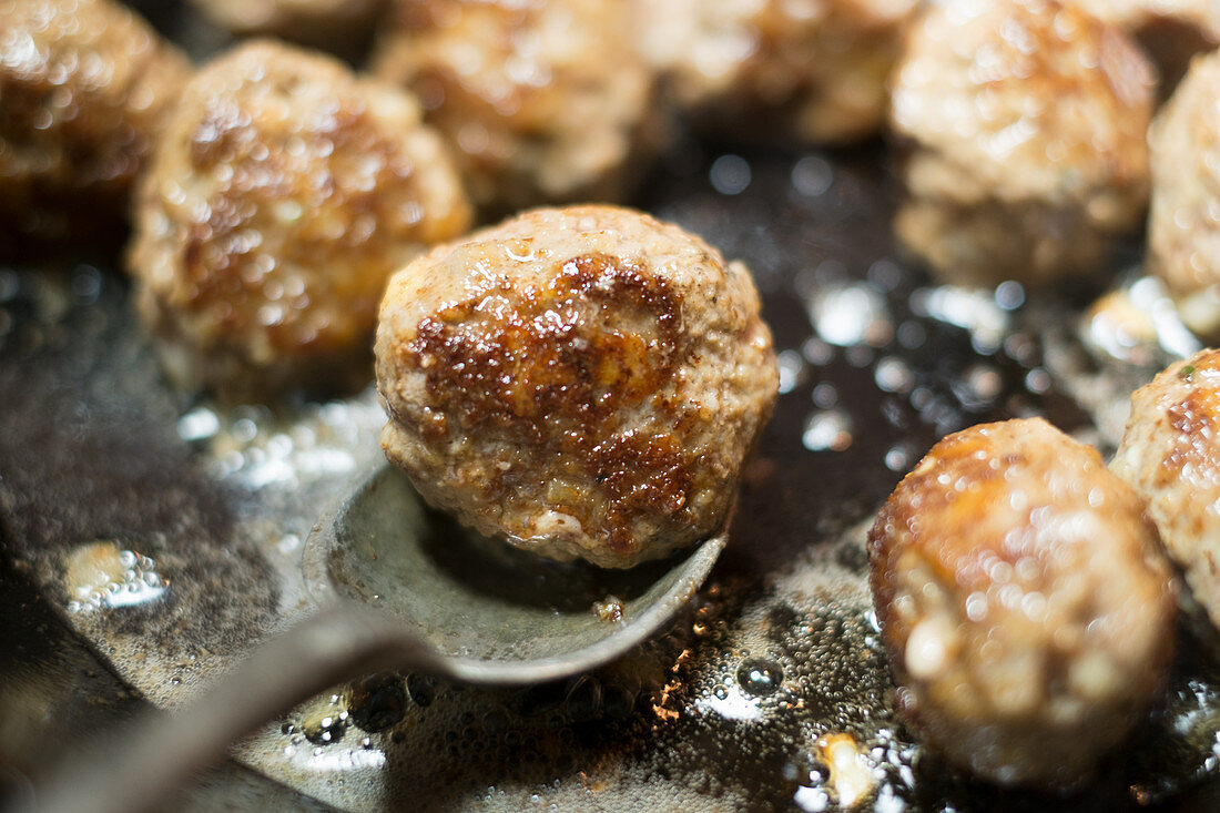 Meatballs being fried in a pan