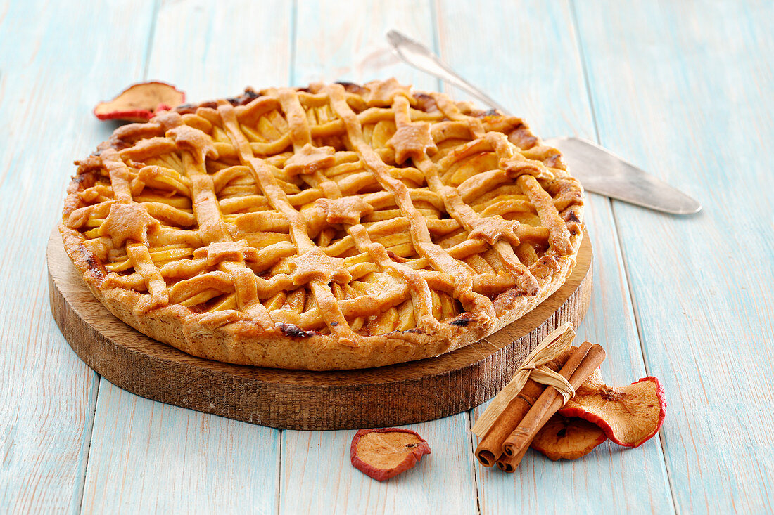 Apple tart with a lattice topping and pastry stars on a wooden plate