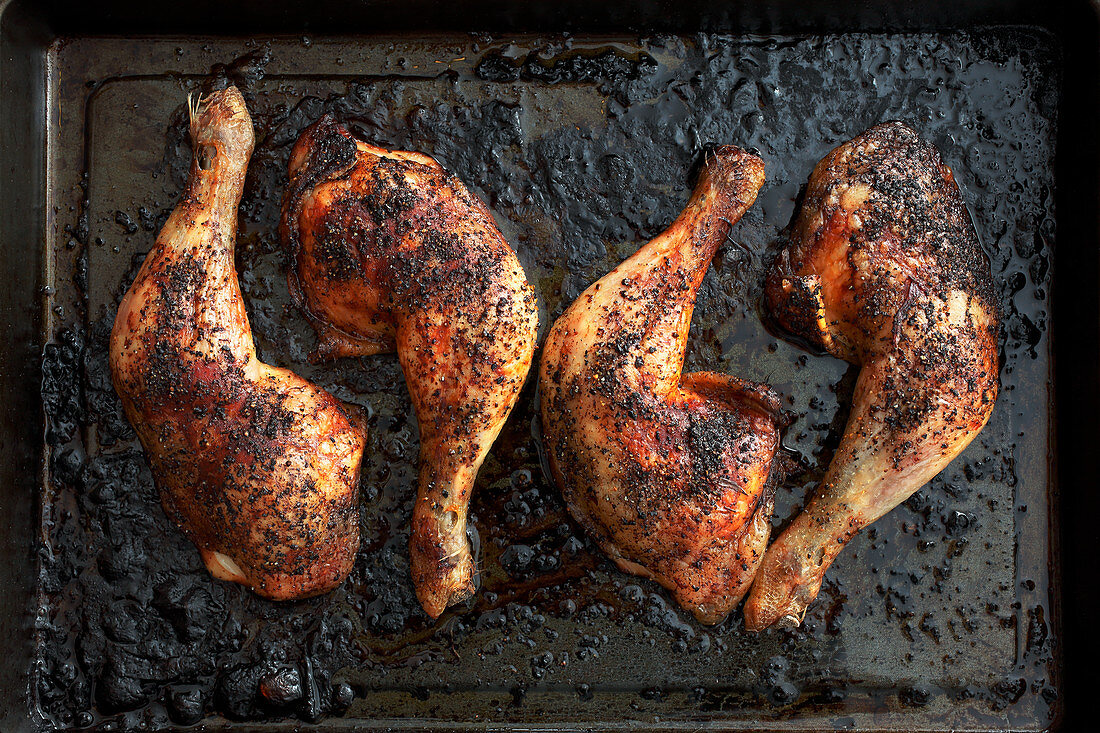 Roasted chicken legs on a baking tray (seen from above)