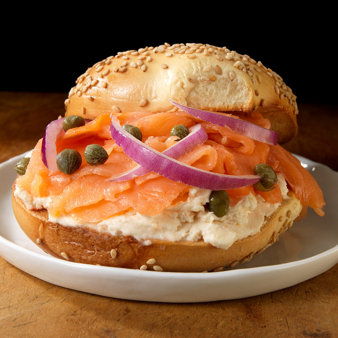 Salmon and cream cheese on sesame bagel with capers and red onions