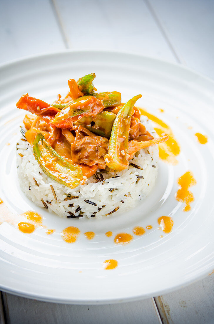 Creamy chicken with okra, red, yellow and green peppers in a creamy tomato sauce on white and brown long grain rice