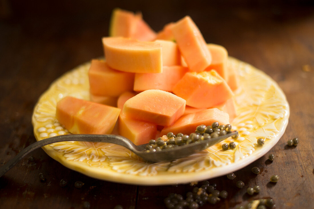 Sliced papaya fruit and papaya seeds on a spoon