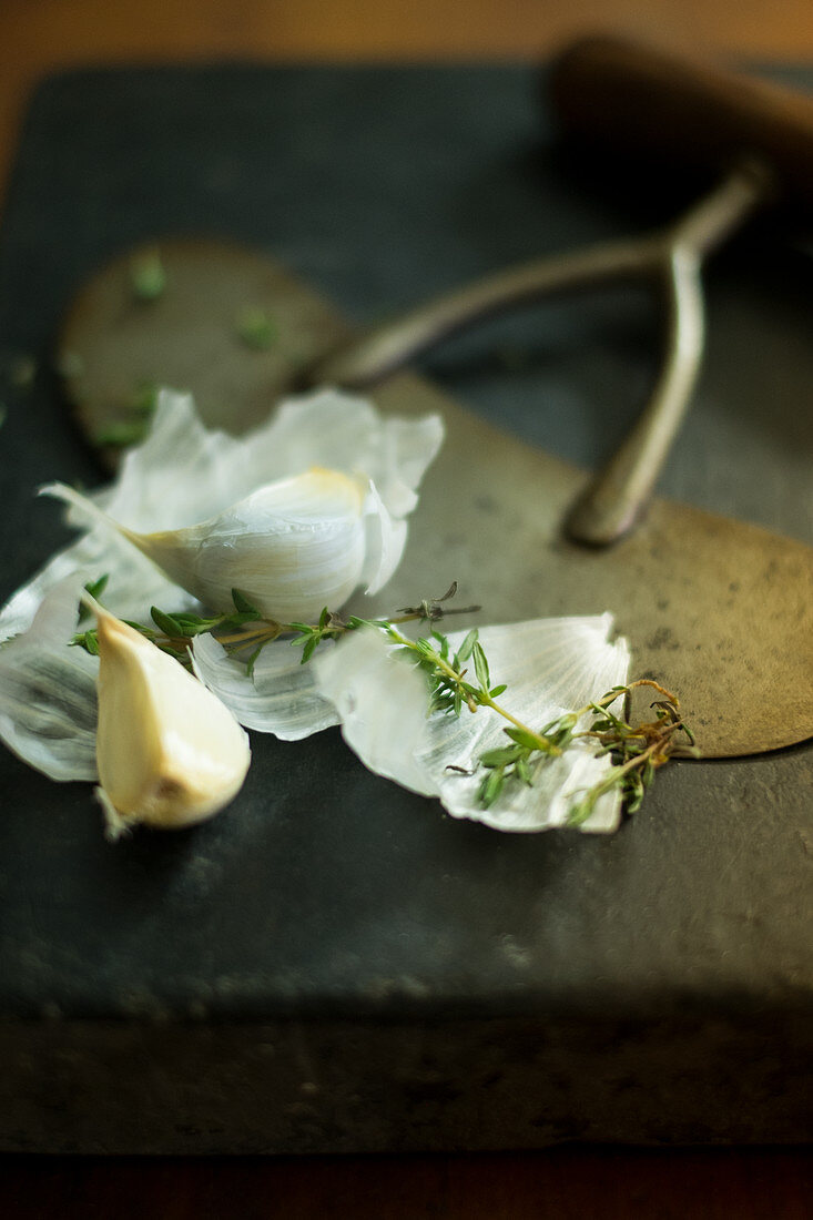 Garlic and thyme on a black chopping board
