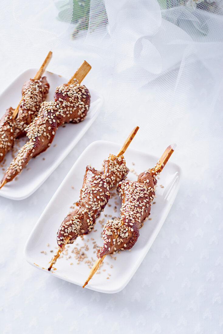 Duck skewers with orange glaze and sesame seeds