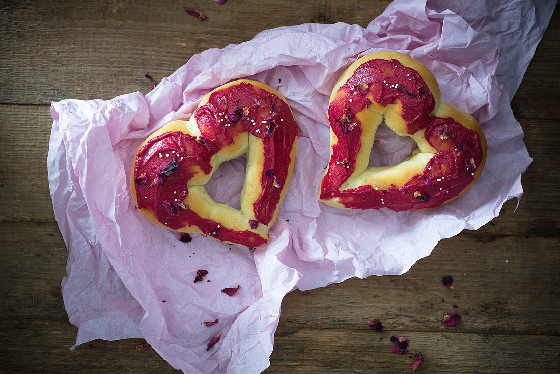 Oven-baked, heart-shaped vegan doughnuts with icing and rose petals