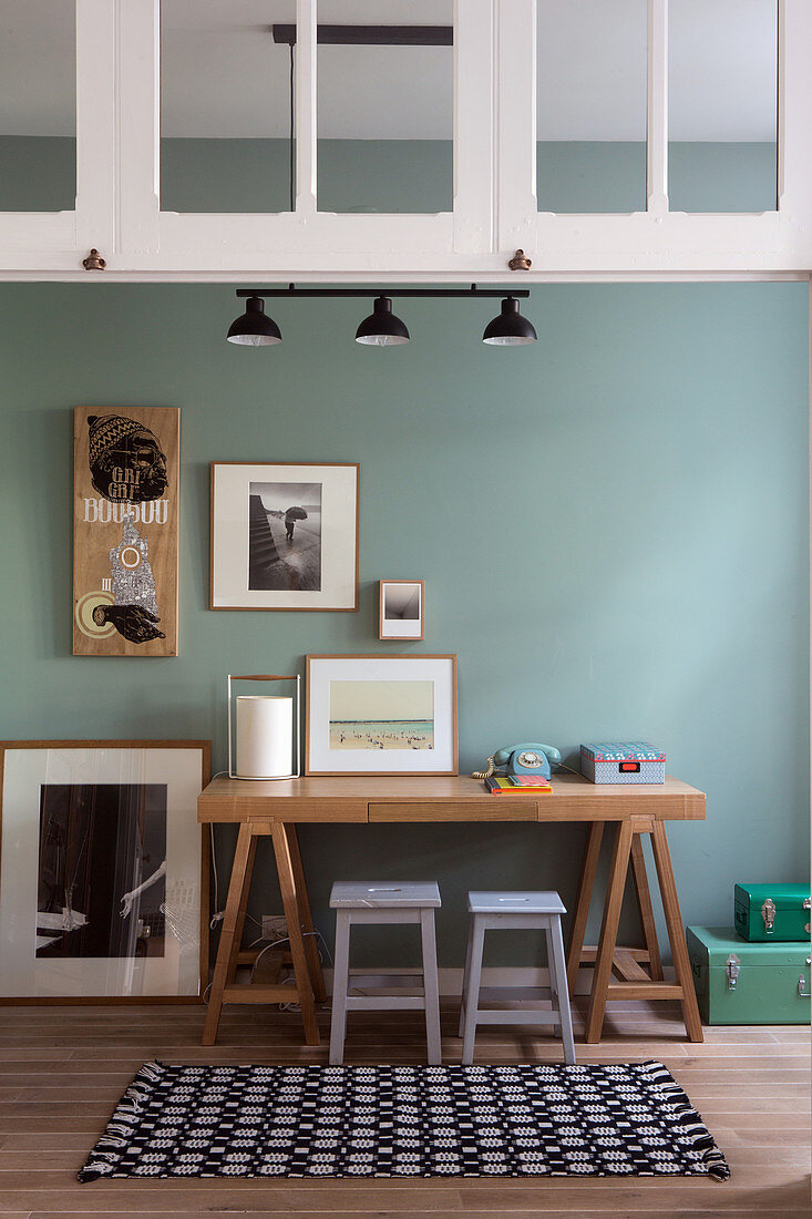 Desk with two stools and framed pictures in study