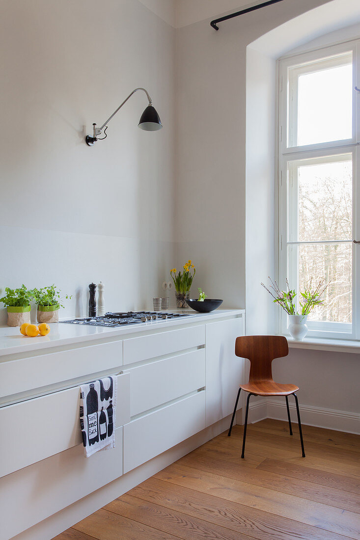 Designer chair next to minimalist kitchen counter without wall units