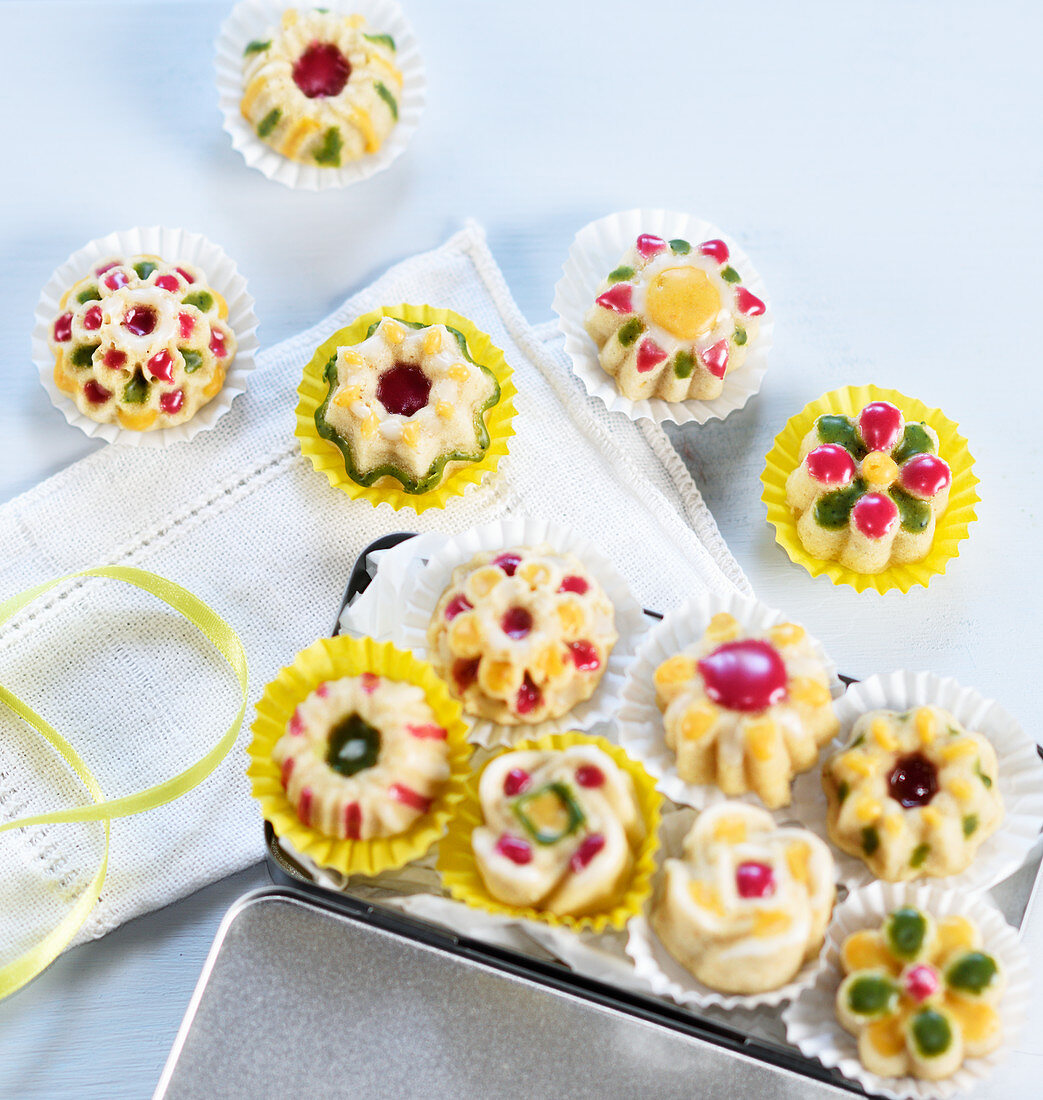 Mini cakes with colourful icing in paper cases (vegan)