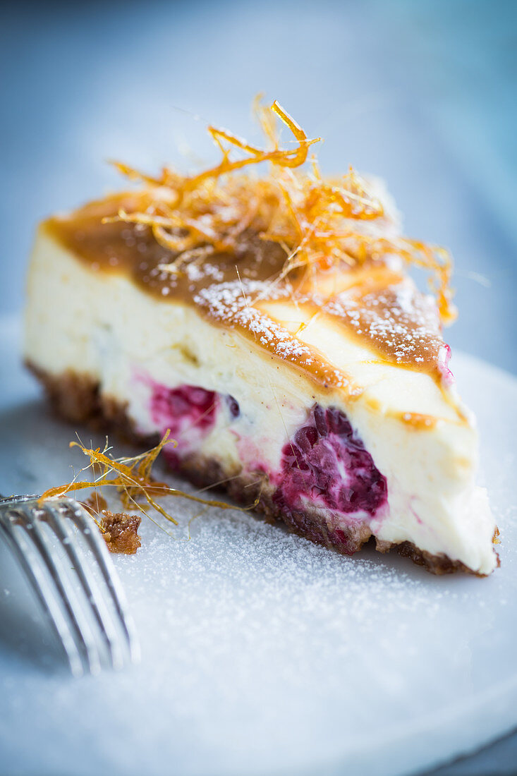A slice of cheesecake with raspberries